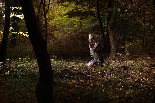 Young woman praying in the forest.