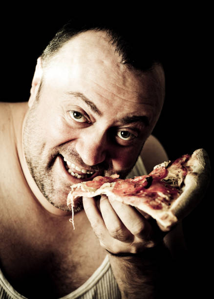 Big man eating pizza stock photo
