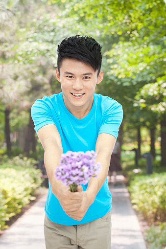 Chinese man offering bouquet of flowers