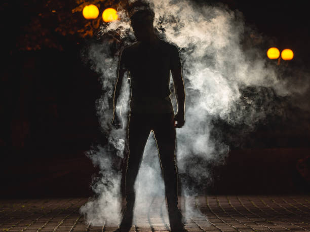 der mann stand auf dem hintergrund der rauch. nachtzeit - street fog profile stock-fotos und bilder
