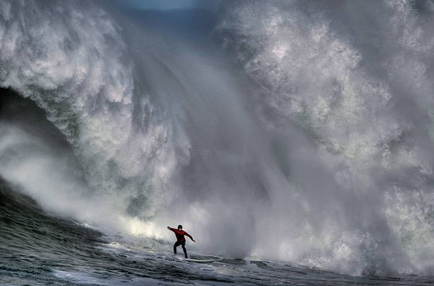 Surfer at the bottom of a huge crashing wave  stock photo