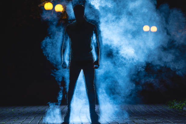 the man stand on the blue smoke background. night time - street fog profile imagens e fotografias de stock