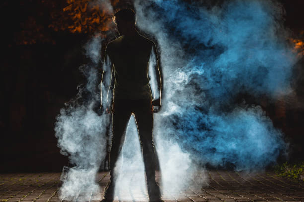 die silhouette eines mannes auf der straße auf dem hintergrund eines rauchs. nacht - street fog profile stock-fotos und bilder