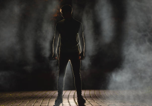mężczyzna stoi na ciemnej ulicy na tle dymu. połów nocny - street fog profile zdjęcia i obrazy z banku zdjęć