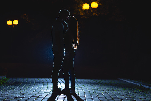 The man and woman kissing on the dark alley. night time