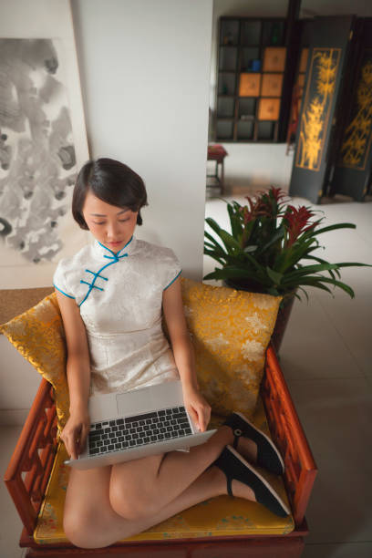 donna cinese in abiti tradizionali usando laptop - cheongsam chinese culture indoors looking at camera foto e immagini stock