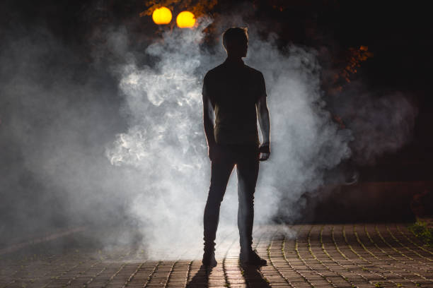 the man stand on the dark alley with a fume. night time - street fog profile imagens e fotografias de stock