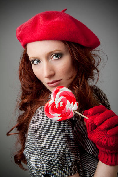 ein elegantes modell mit roten baskenmütze mit lutscher - mua1 stock-fotos und bilder
