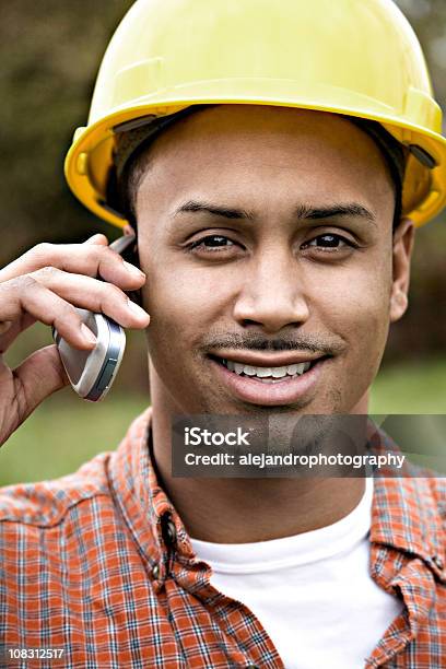 Foto de Latino Trabalhador De Construção Sorrindo No Telefone Celular e mais fotos de stock de 20 Anos