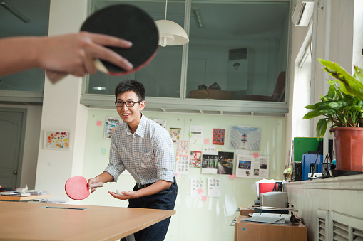 Chinese businessmen playing ping pong in office