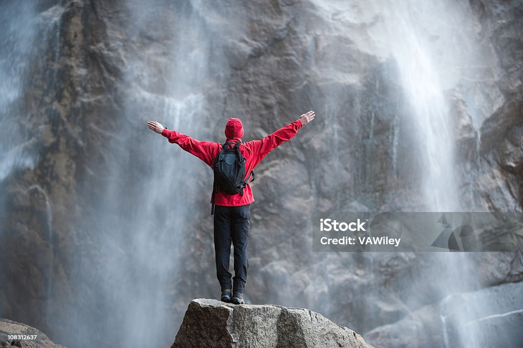 Awesome A man standing in Awe in front of a waterfall  Adventure Stock Photo