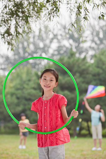 Chinese girl playing with plastic hoop in park