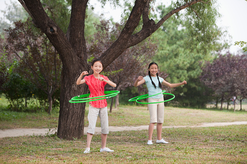 Chinese girls playing with plastic hoops in park