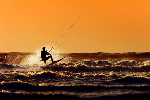 A young woman kitesurfer rides the waves doing a trick. Marine sports. kitesurfing.