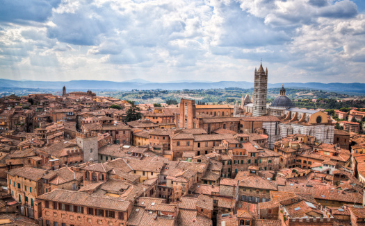 Panoramic view of the historic part of the city of Siena with the Duomo di Siena against a stormy sky in the Tuscany region of Italy