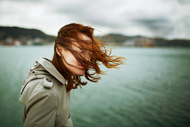 Profile of a young woman with eyes closed who looks peaceful and happy with the wind in her hair