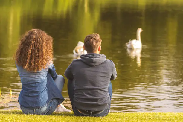 Photo of The man and woman sit on the river shore