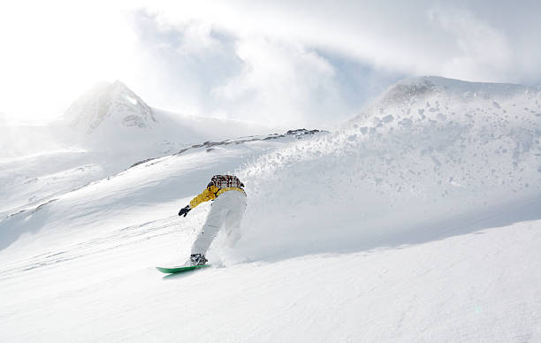 osoba snowboarding wzdłuż gór w pochmurny dzień - freeride zdjęcia i obrazy z banku zdjęć