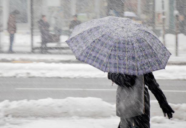 One women walking under umbrella in heavy snowfall in city street