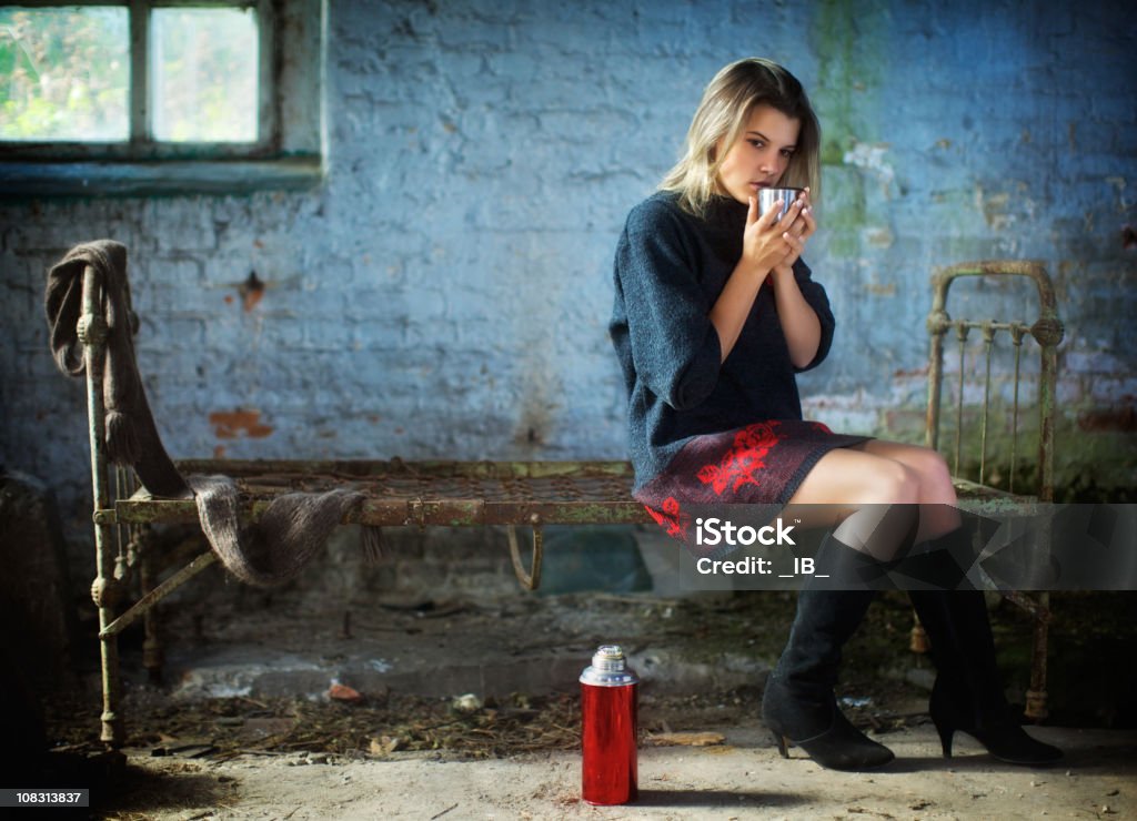 Lonely garota senta-se em uma casa velha e beber chá. - Foto de stock de 20 Anos royalty-free