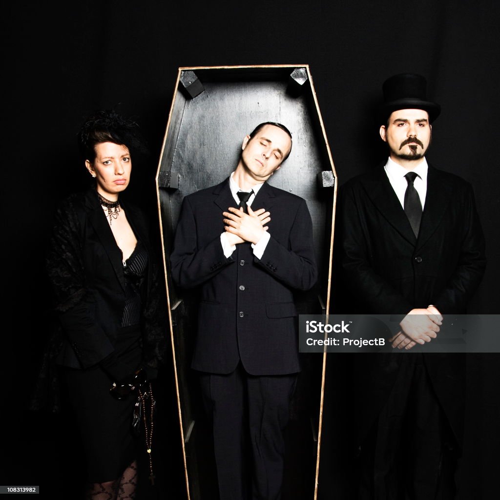 Dead husband in coffin with grieving wife and undertaker Widow, dead husband and undertaker. Coffin Stock Photo