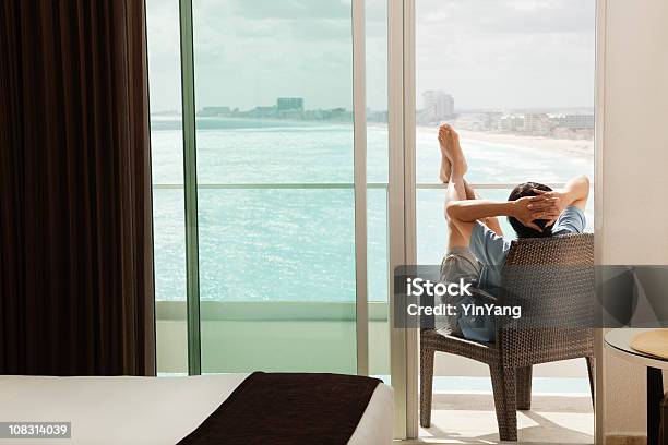 Hombre Relajante Con Balcón Y Vista Al Mar En Playa Vacaciones Foto de stock y más banco de imágenes de Balcón