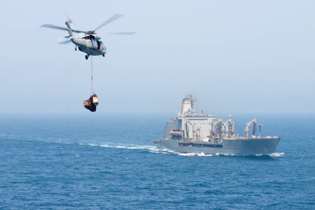 Navy helicopter delivering goods to ship stock photo