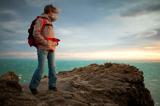 Woman outdoor adventures: hiking in Norway, on the mountain by a fjord