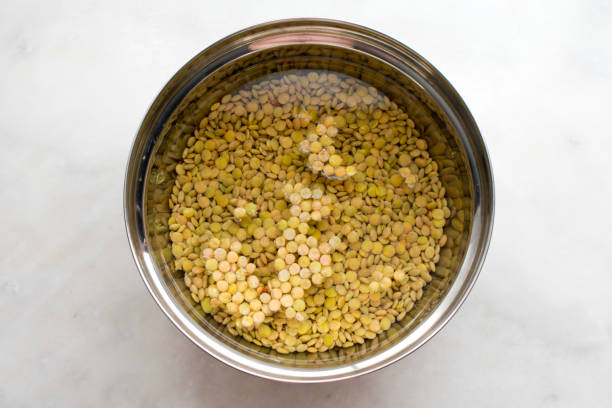 Soaking Green Lentils Green lentils soaking in a bowl of water drenched stock pictures, royalty-free photos & images