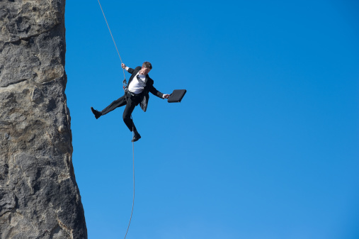 A businessman rappelling off a cliff 