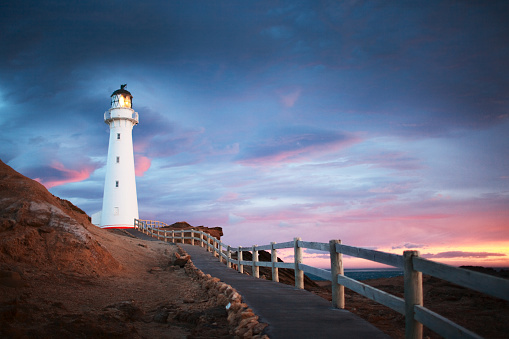 Landscaping of Silent Northeast Atlantic Ocean coast with skyline at low tide with rocks washed up by the surf and real operating Lighthouse at the top of the cliff showing the ships a safe way to go