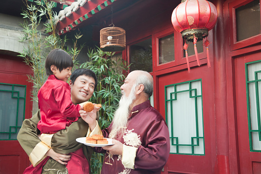 Chinese family sharing plate of food outdoors