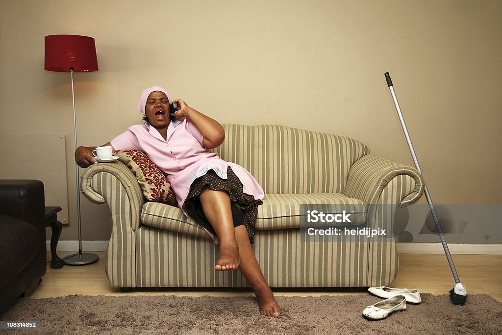 Maid taking a break Domestic worker having tea and talking on the phone when madam is not home. African Ethnicity Stock Photo