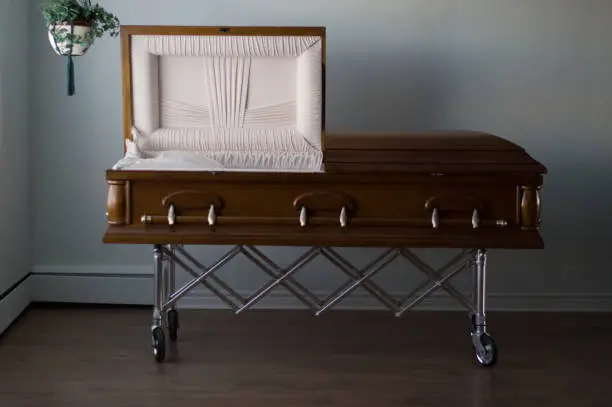 An open casket on a gurney in a funeral home