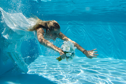 Bride underwater in the style of the Trash the Dress wedding photography trend