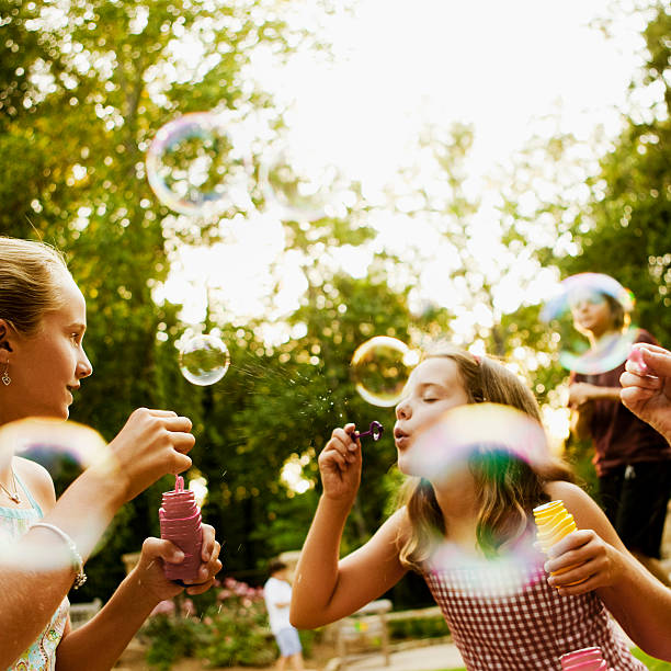 niños soplando burbujas en el parque - bubble wand bubble child playful fotografías e imágenes de stock