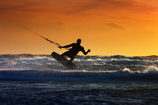 Silhouette of a windsurfer riding along the waves stock photo