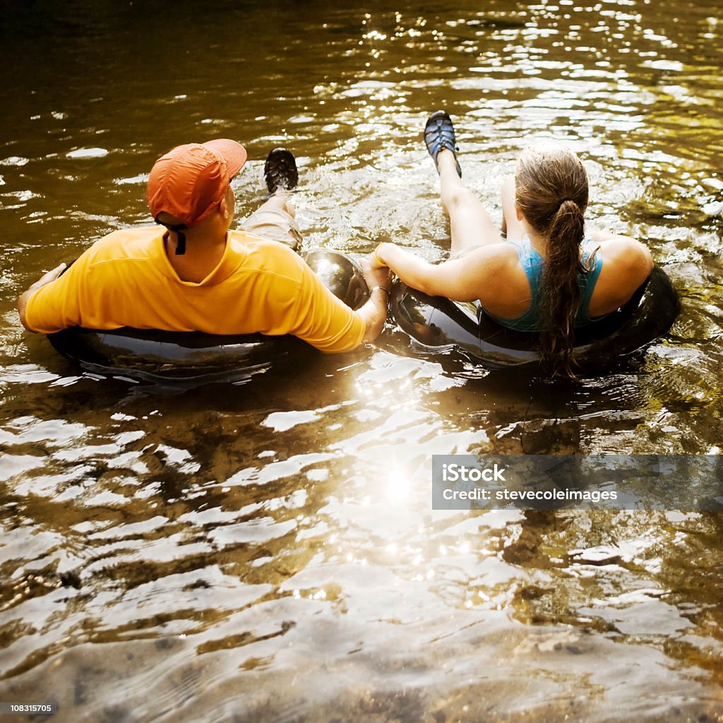 Casal de mãos dadas enquanto flutua nas boias - Foto de stock de Adulto royalty-free