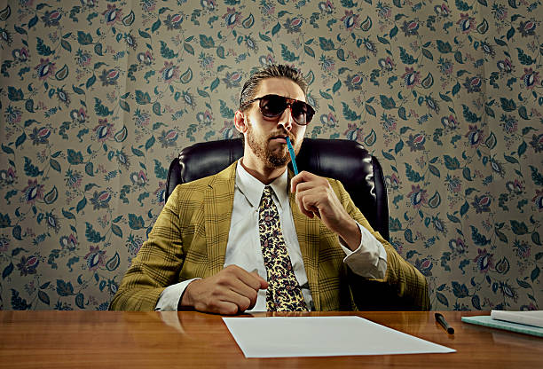executive powerhouse vintage salesman sits in his desk with his power tie on contemplating a take over. retro salesman stock pictures, royalty-free photos & images