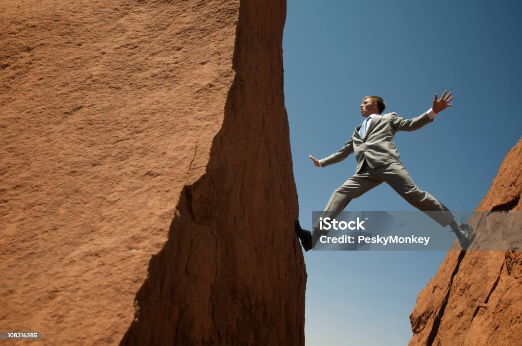 A souligné Homme d'affaires en équilibre à l'extérieur du Rocks - Photo de Être pris en étau libre de droits