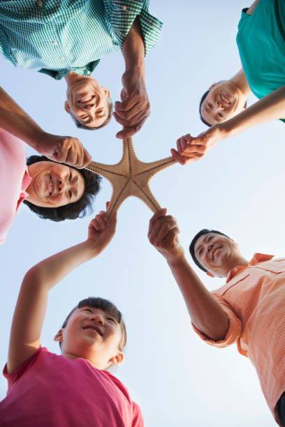 istock Chinese family holding starfish on beach 1083164948