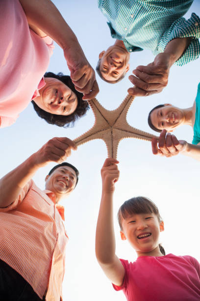 Chinese family holding starfish on beach