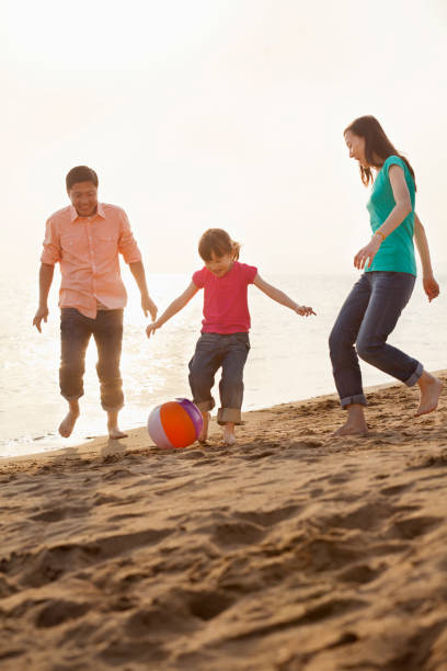 istock Chinese family playing with ball on beach 1083165004