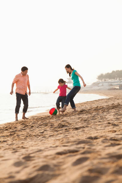 istock Chinese family playing with ball on beach 1083165024