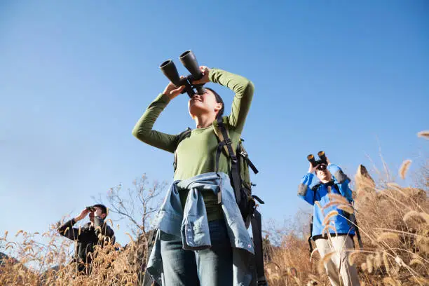 Chinese friends using binoculars in rural landscape