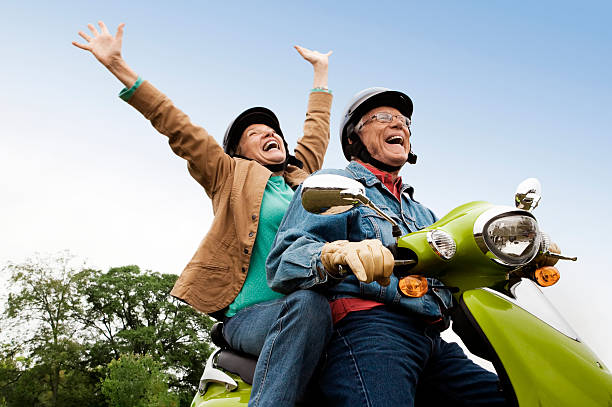 Senior Couple on Scooter Senior couple having fun riding motor scooter. Horizontal shot. couple adventure activity adult stock pictures, royalty-free photos & images