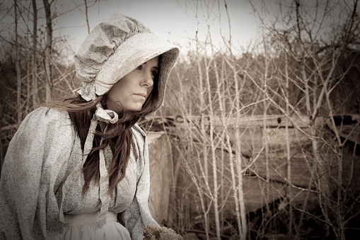 Closeup portrait  young caucasian woman with short haircut. Girl wears straw hat and dark blue dress with polka dots. Female looking at camera posing nature outdoors