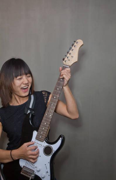 istock Chinese woman playing electric guitar 1083190672