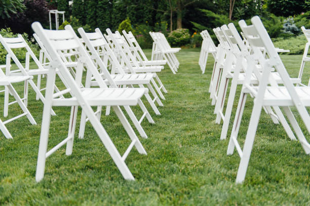 istock White wedding chairs decorated with fresh flowers on a green grass. 1083235356