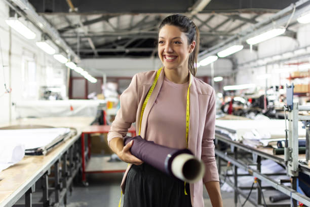 giovane donna sorridente in una fabbrica di moda - industria della moda foto e immagini stock